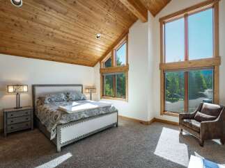 This stunning bedroom boasts a vaulted, wood-paneled ceiling and expansive windows that flood the space with natural light.