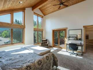 This stunning bedroom boasts a vaulted, wood-paneled ceiling and expansive windows that flood the space with natural light.