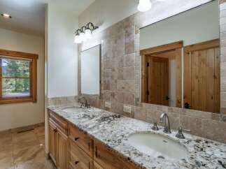 This stunning bathroom features a double vanity with a beautiful granite countertop, offering ample space for daily routines.