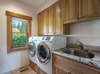 This laundry room features a modern design with a sleek stainless steel sink and granite countertops.