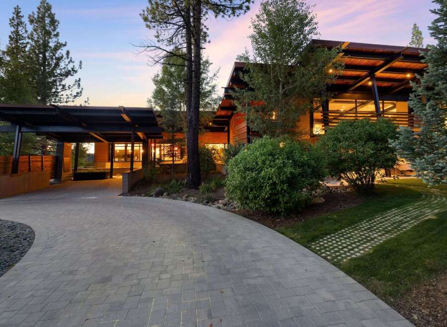 Experience modern luxury with this stunning architectural home, featuring a dramatic cantilevered roof and expansive glass windows that seamlessly blend indoor and outdoor living.