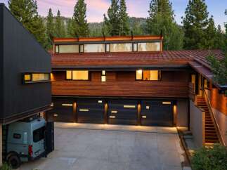Experience modern luxury in this stunning mountain home, featuring a striking dark facade and warm wood accents.