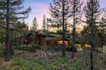 Nestled amongst towering pine trees, this architectural gem boasts a striking modern design with a sloped roof and expansive glass windows.