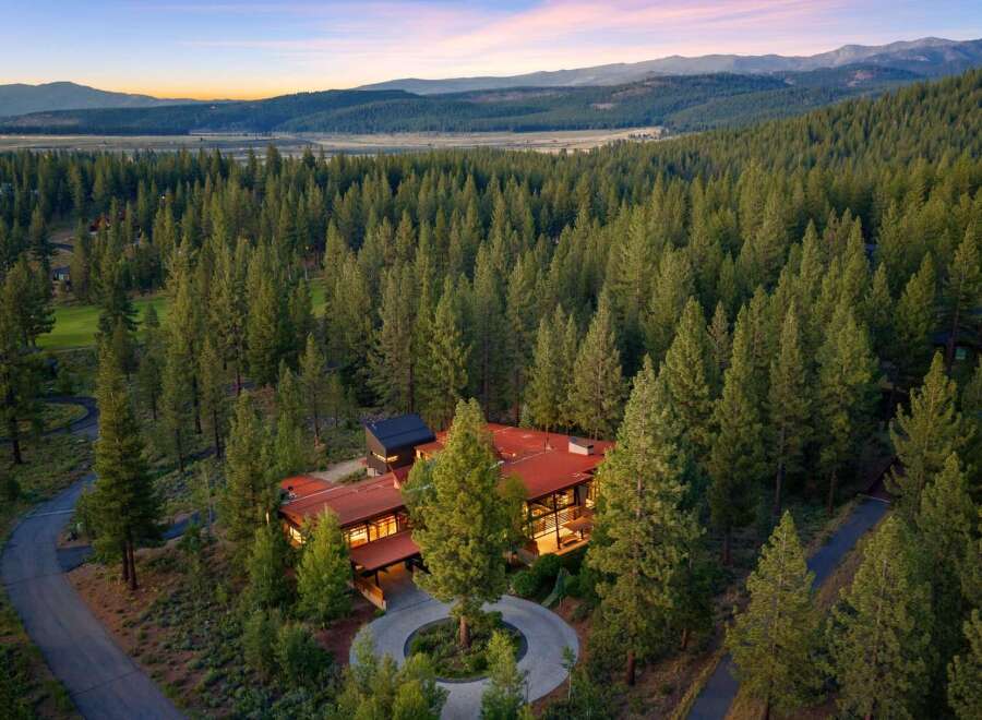 Nestled amidst a dense forest of towering pine trees, this stunning modern home offers a serene retreat with breathtaking mountain views.
