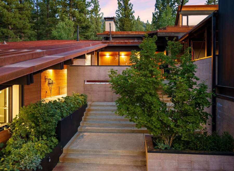 Experience modern mountain living with this stunning architectural home, featuring a striking rusted metal roof and natural wood accents.