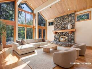 Experience luxury living in this stunning home featuring a grand stone fireplace, soaring ceilings, and expansive windows that flood the space with natural light.