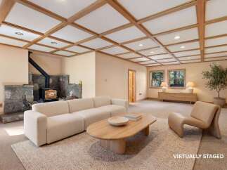 Step into a cozy living space featuring a stunning stone fireplace and a unique coffered ceiling.