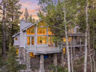 Nestled amidst towering trees, this stunning home boasts a unique architectural design with expansive windows that flood the interior with natural light.