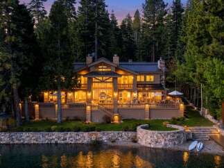 This stunning waterfront property boasts a luxurious multi-story home with expansive windows, offering breathtaking views of the lake.