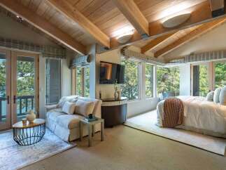 Experience luxury in this stunning bedroom featuring a vaulted wooden ceiling and expansive windows that frame breathtaking views.