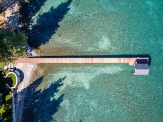 This stunning property boasts a private dock extending into the crystal-clear turquoise waters, perfect for boating and water activities.
