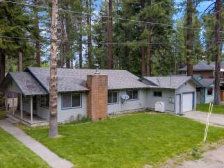 This charming home offers a serene retreat with its lush green lawn and inviting facade.