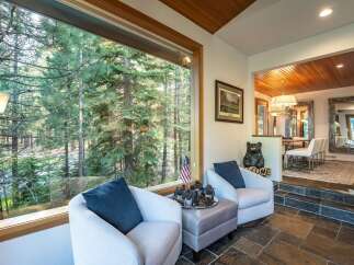 Experience the tranquility of nature from this stunning property, featuring expansive windows that frame breathtaking views of a lush forest.