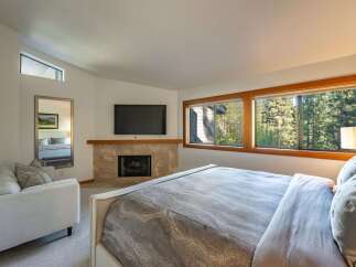 This luxurious bedroom boasts a cozy fireplace and a large flat-screen TV, perfect for relaxing evenings.