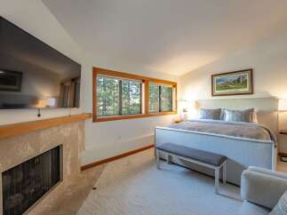 This stunning bedroom boasts a cozy fireplace and a large flat-screen TV, perfect for relaxing evenings.