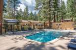 Enjoy a refreshing dip in the sparkling blue swimming pool, surrounded by lush pine trees and comfortable lounge chairs.
