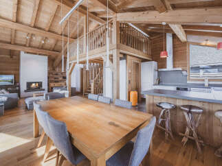 Experience luxury mountain living in this stunning chalet featuring a spacious open-plan living area with a cozy fireplace and a modern kitchen.