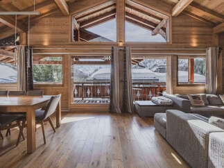 Experience the ultimate alpine retreat in this stunning wooden chalet, featuring a spacious living area with a large dining table and comfortable sectional sofa.
