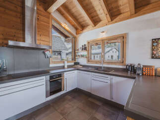 Experience the charm of this mountain kitchen, featuring a sleek stainless steel range hood and modern white cabinetry.