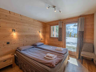 Experience cozy mountain living in this charming bedroom featuring two comfortable beds and warm wooden paneling.