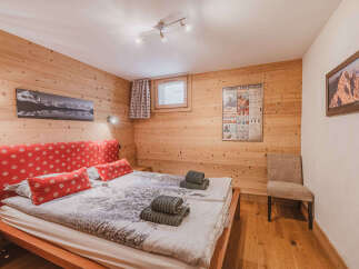 Experience cozy mountain living in this charming bedroom featuring warm wood paneling and a comfortable bed adorned with festive snowflake-patterned pillows.