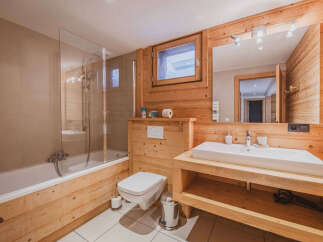 Experience rustic charm in this beautifully appointed bathroom, featuring a deep soaking tub with a glass shower enclosure and warm, natural wood paneling throughout.