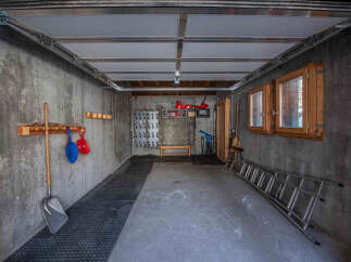 This spacious garage offers ample storage solutions, including a wall-mounted rack with hooks for tools and accessories, and a pegboard system for organizing smaller items.