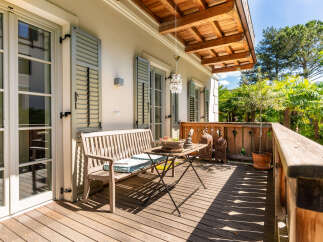 Enjoy your morning coffee on this charming wooden balcony, complete with a comfortable bench and a rustic table.