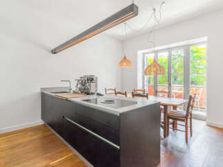 Experience modern living in this stunning kitchen and dining area, featuring a sleek dark island with a built-in induction cooktop and a professional-grade espresso machine.