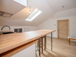 Discover this modern kitchen featuring a spacious wooden countertop island, perfect for casual dining and entertaining.