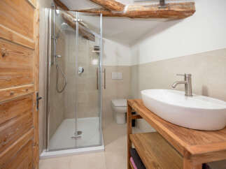 Experience rustic charm in this beautifully appointed bathroom, featuring a spacious walk-in shower with modern fixtures and a sleek vessel sink atop a warm wooden vanity.