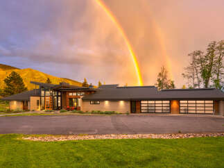Experience luxury living in this stunning modern home, perfectly situated against a backdrop of majestic mountains and a breathtaking double rainbow.