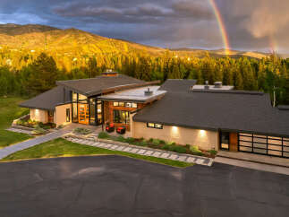 Experience luxury mountain living in this stunning modern home, perfectly situated to capture breathtaking views of rolling hills and a vibrant rainbow.