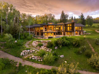 Experience luxury living in this stunning modern mountain home, featuring expansive windows that capture breathtaking sunset views.