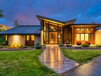 Experience modern luxury in this stunning home featuring a dramatic entryway with a soaring glass ceiling and warm wood accents.