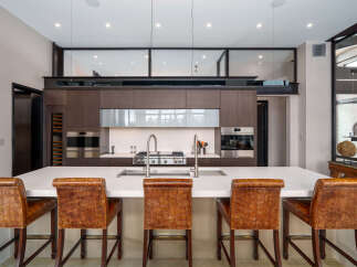 Experience luxury in this modern kitchen featuring a spacious island with comfortable seating and a sleek, integrated sink and faucet system.