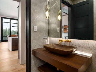 Experience luxury in this modern bathroom featuring a striking vessel sink atop a rich wooden vanity.