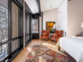 Experience luxurious mountain living in this stunning bedroom featuring large windows with breathtaking winter views.
