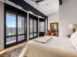 Experience breathtaking mountain views from this luxurious bedroom, featuring expansive windows that flood the space with natural light.
