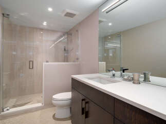Experience modern luxury in this stunning bathroom, featuring a spacious glass-enclosed shower with elegant tilework and a sleek vanity with a pristine white countertop.