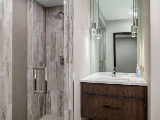 Experience luxury in this modern bathroom featuring a spacious walk-in shower with elegant marble-look tiles and a sleek glass enclosure.