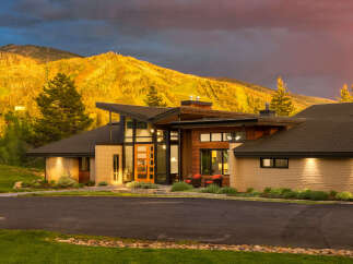 Experience luxury mountain living in this stunning contemporary home, perfectly situated against a backdrop of golden ski slopes and dramatic skies.