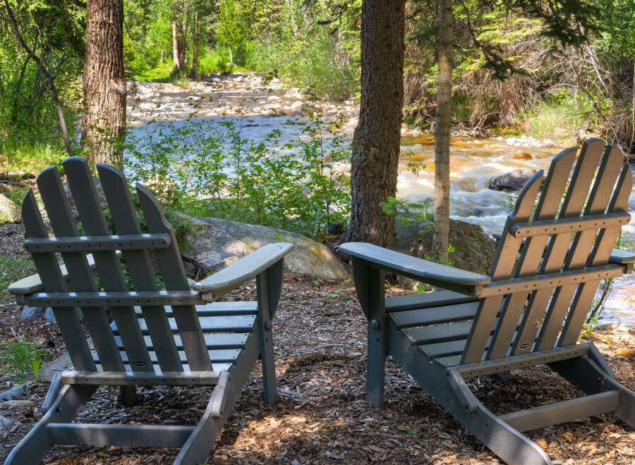 Experience serene living with this charming property featuring two Adirondack chairs perfectly positioned for enjoying the tranquil riverfront view.