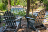 Experience serene living with this charming property featuring two Adirondack chairs perfectly positioned for enjoying the tranquil riverfront view.