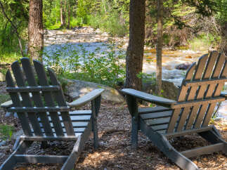 Experience serene living with this charming property featuring two Adirondack chairs perfectly positioned for enjoying the tranquil riverfront view.