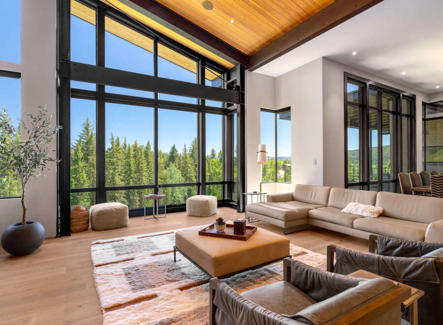 Experience luxury living with this stunning modern home featuring expansive floor-to-ceiling windows that showcase breathtaking forest and mountain views.