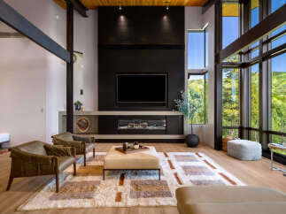 Experience luxury living in this stunning modern living room, featuring a dramatic floor-to-ceiling fireplace and expansive windows that showcase breathtaking mountain views.