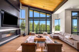 Experience luxury mountain living in this stunning great room, featuring a modern fireplace and expansive floor-to-ceiling windows that showcase breathtaking forest views.