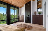 Experience luxury living with this stunning bedroom featuring a modern fireplace and expansive windows offering breathtaking forest views.