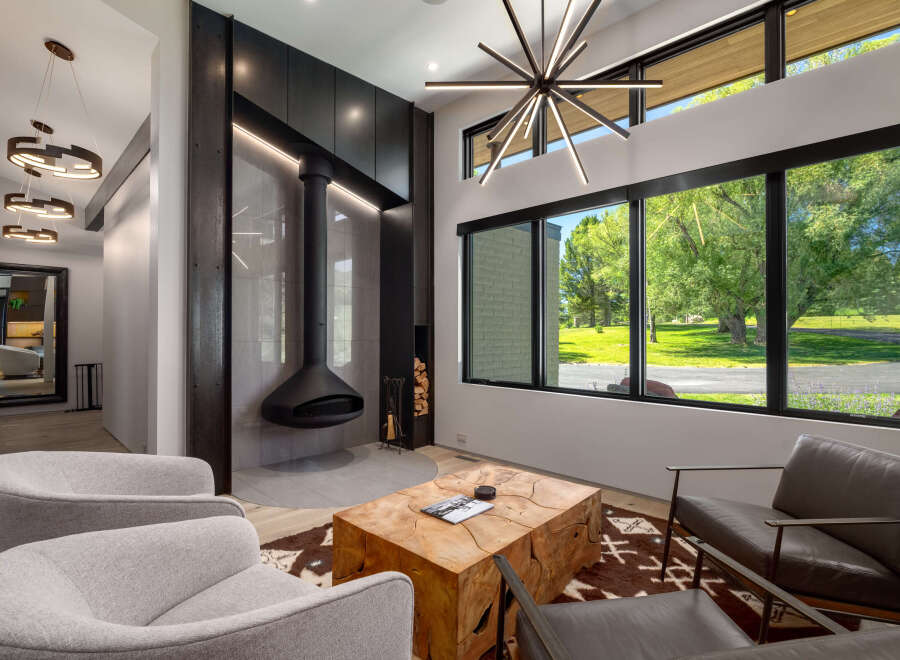 Experience modern luxury in this stunning living room, featuring a unique suspended fireplace and a striking starburst chandelier.